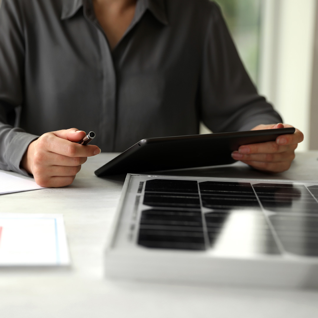 Woman working on project with solar panels at table in office, c